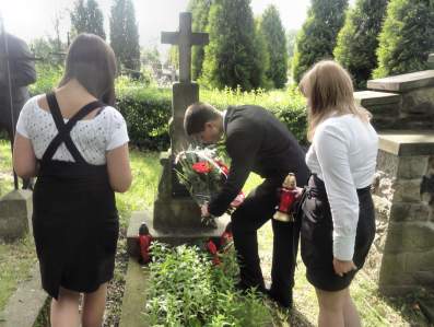  Uczniowie skadaj kwiaty i znicze na grobie Leona Roka polegego w kampanii wrzeniowej.